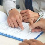 Businessman showing his partner where to sign the contract